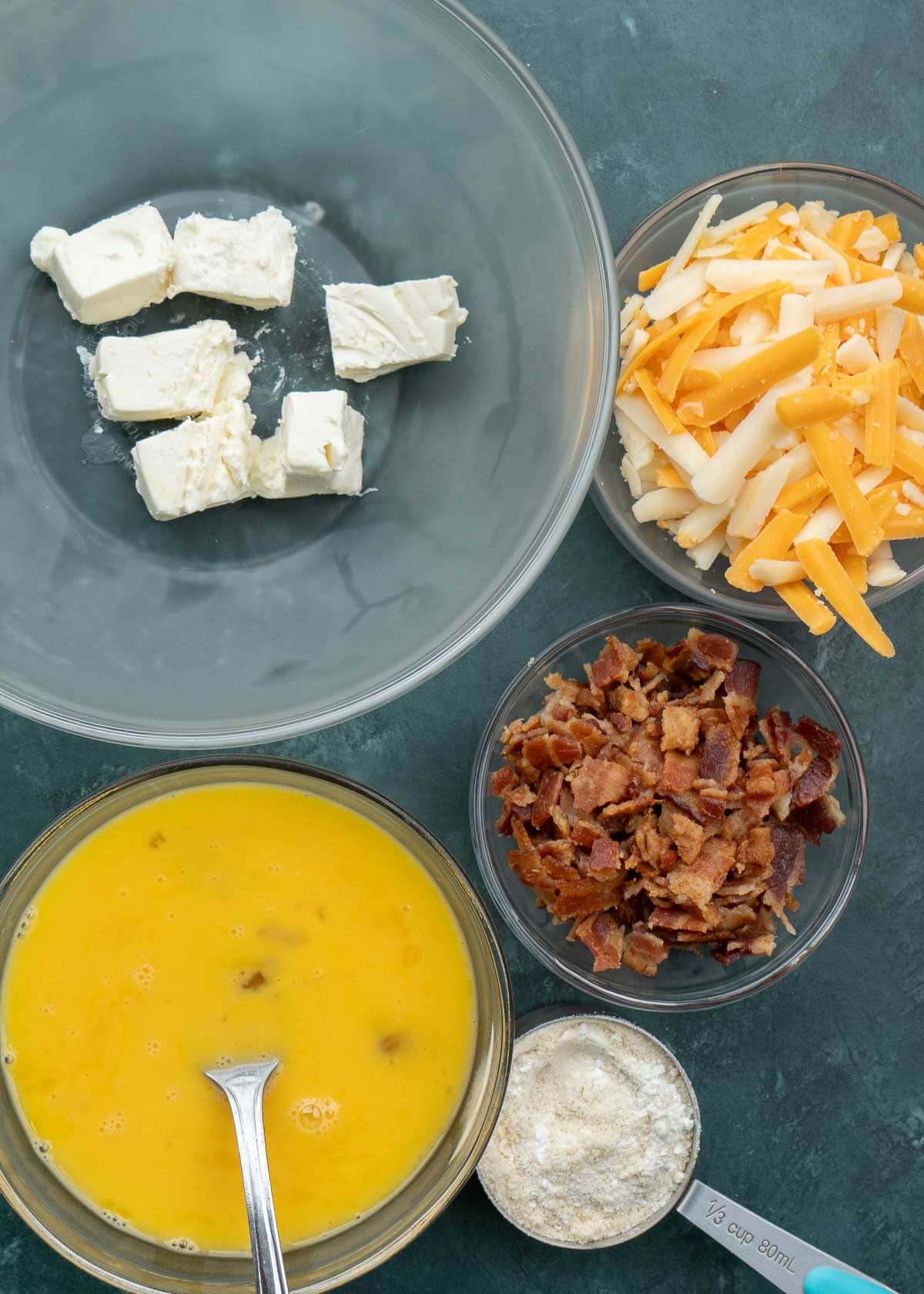 bacon egg and cheese ingredients in a set of clear mixing bowls