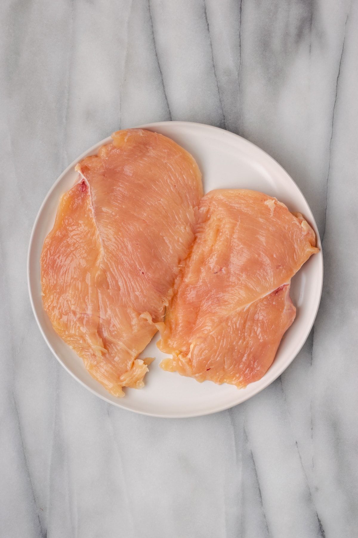 Two pounded out pieces of chicken breast on a plate