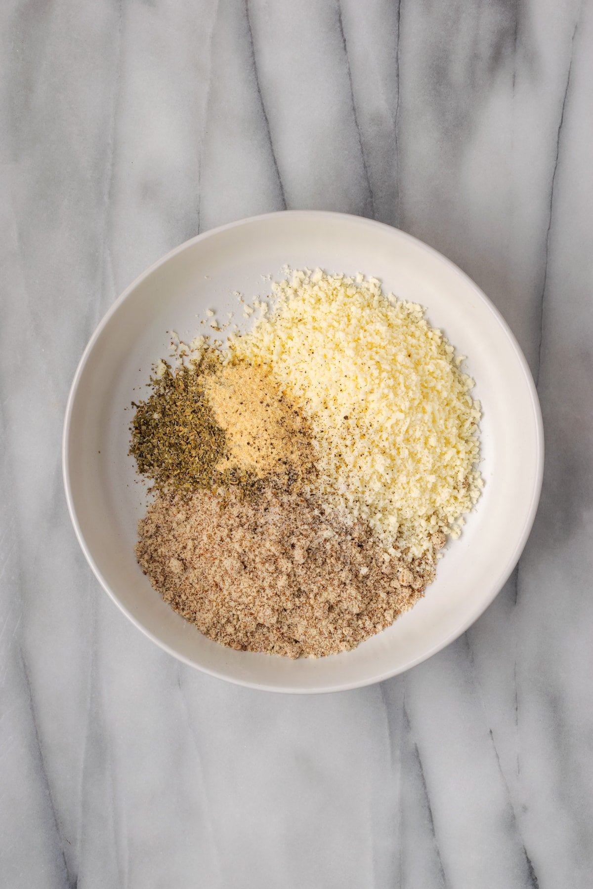 A bowl of almond flour, parmesan cheese, garlic powder, and Italian seasoning