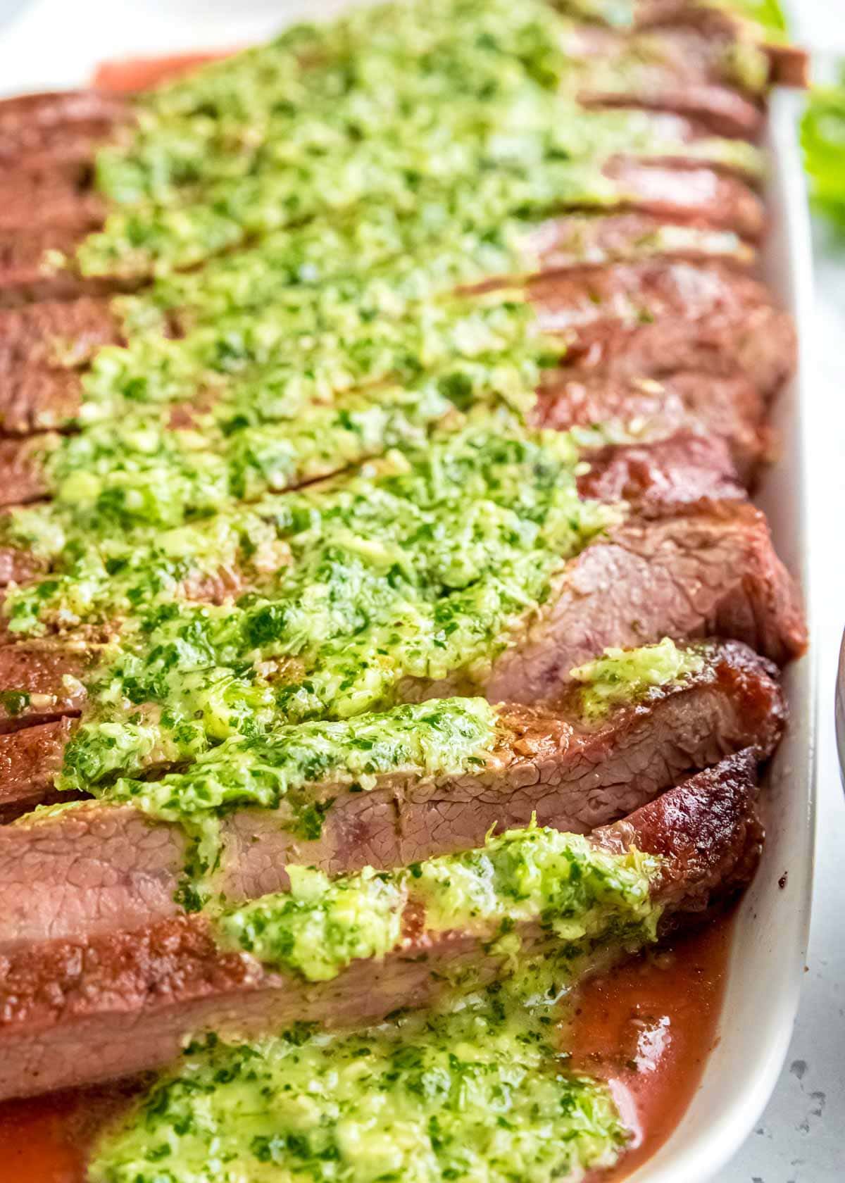 Juicy marinated Flank Steak is grilled to perfection and topped with zesty homemade Chimichurri sauce! This low-carb recipe is perfect for cookouts, parties, or a delicious weekend meal!