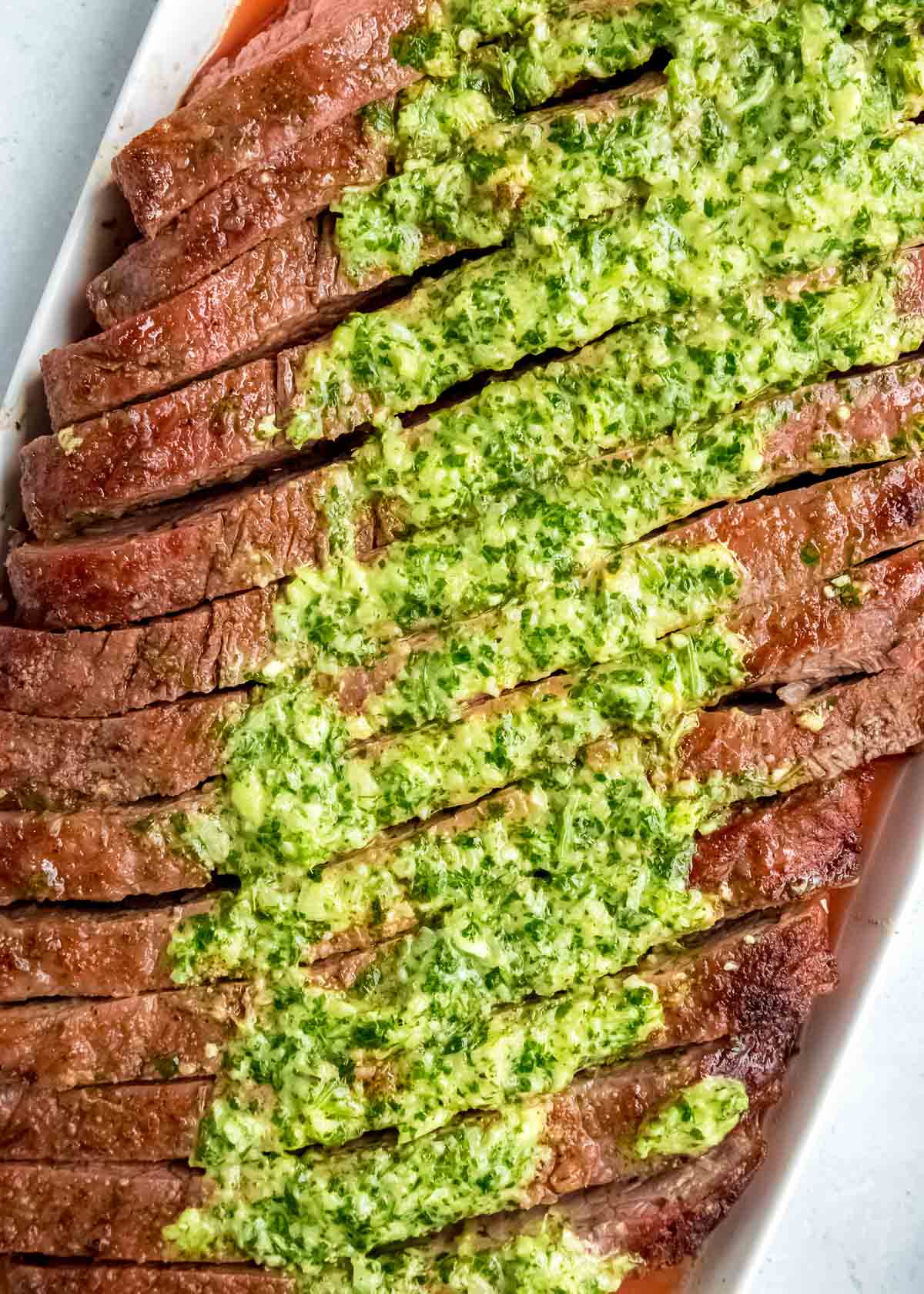 Juicy marinated Flank Steak is grilled to perfection and topped with zesty homemade Chimichurri sauce! This low-carb recipe is perfect for cookouts, parties, or a delicious weekend meal!