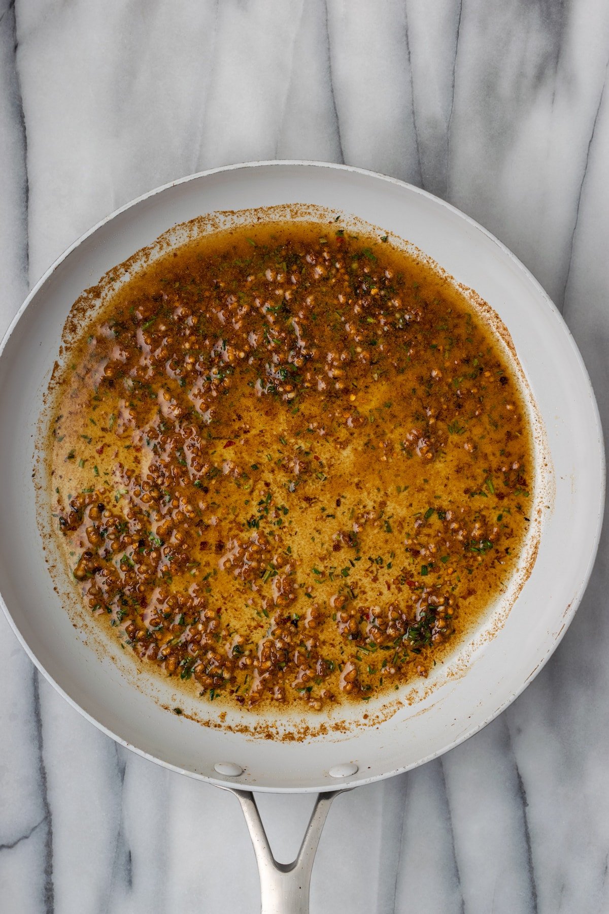 Garlic, herbs, chili flakes, and soy sauce cooking in a skillet