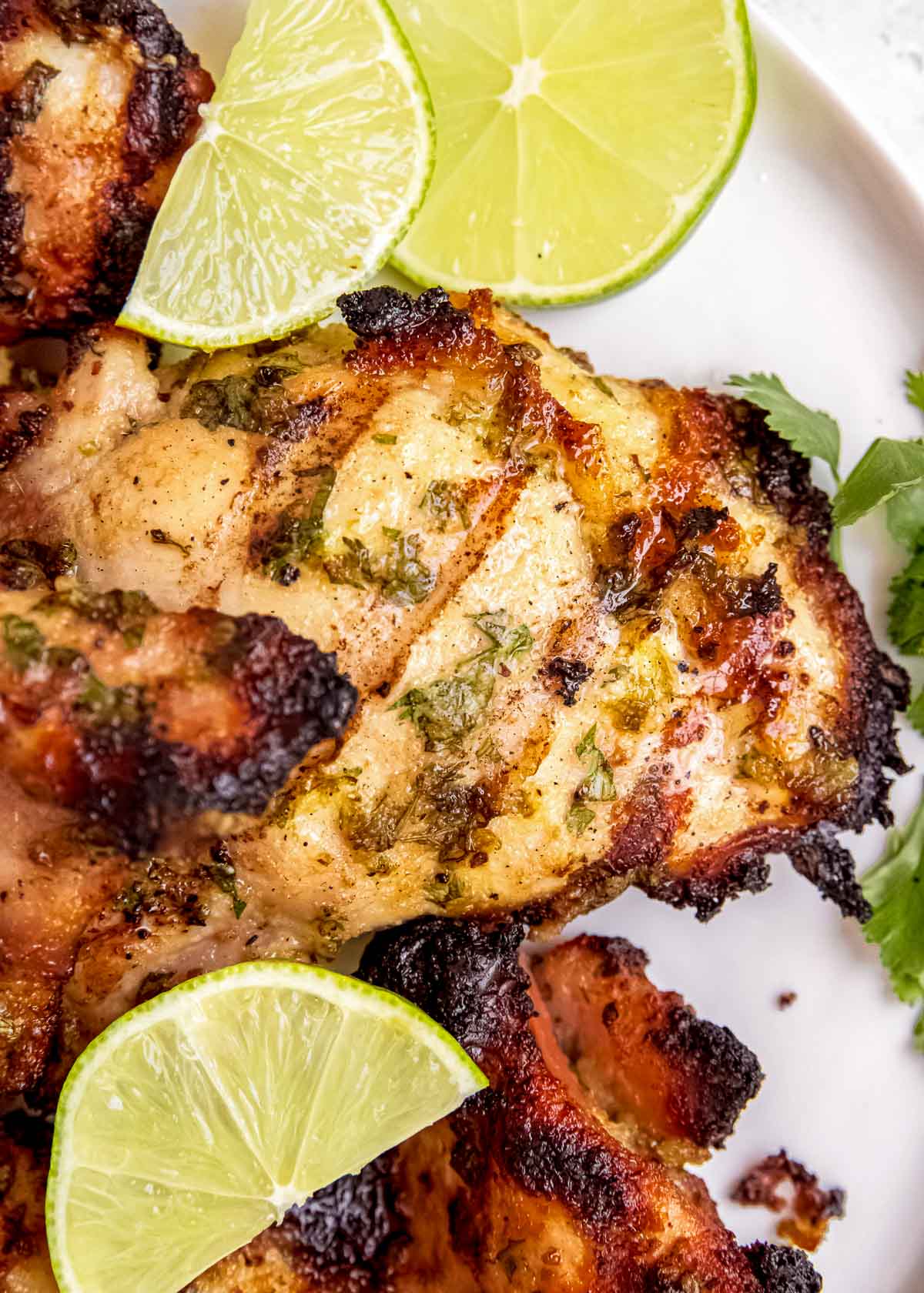 close up photo of grilled chicken and lime wedges on a plate
