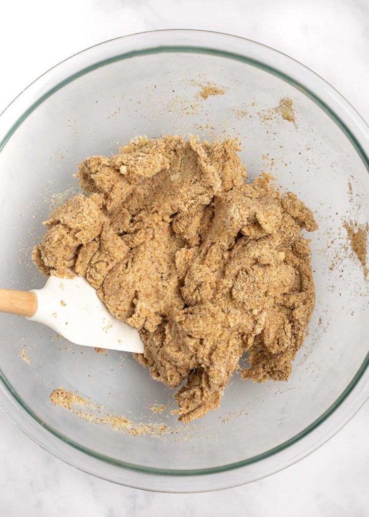 A mixing bowl with a thick dough being stirred by a rubber spatula