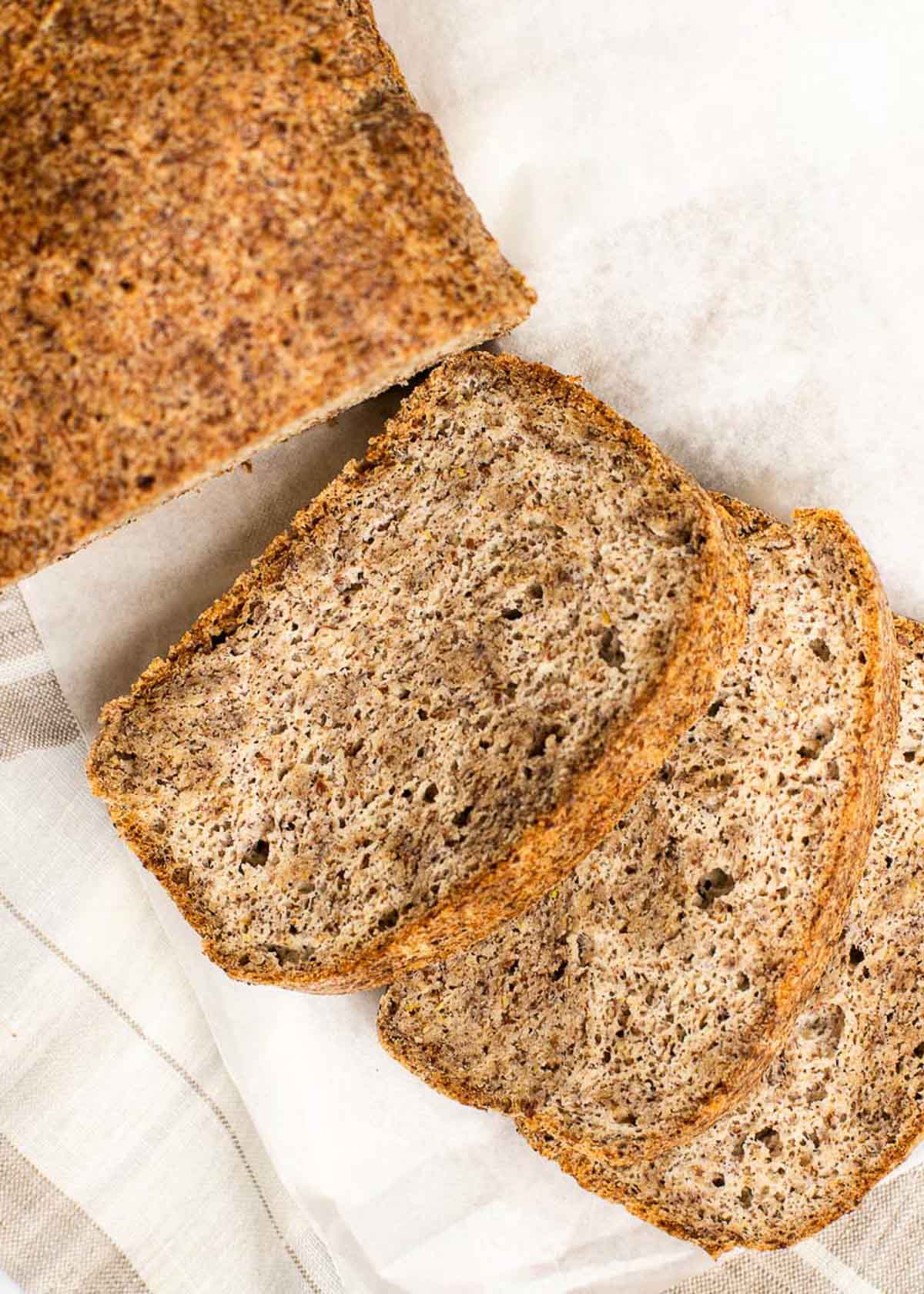 Three slices of freshly baked bread next to the rest of the loaf