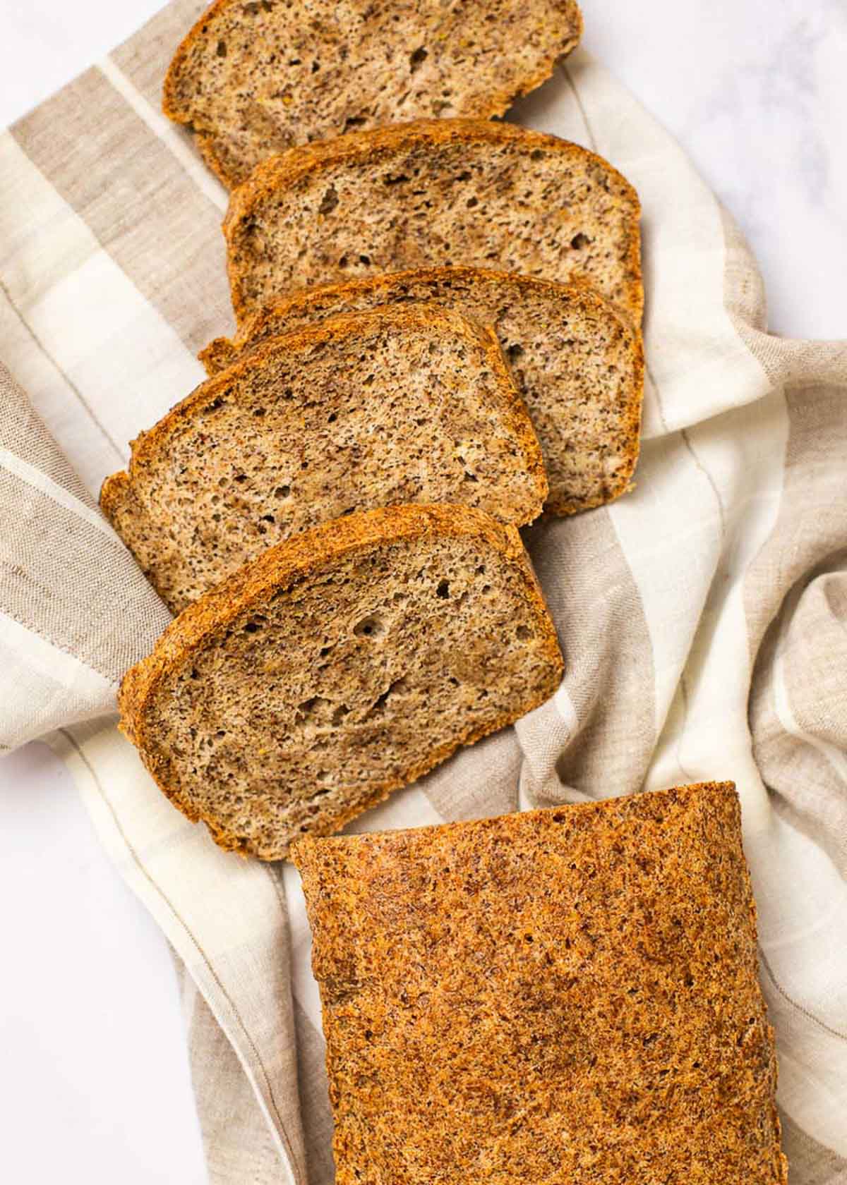 Four slices of bread on a kitchen towel next to the rest of the loaf