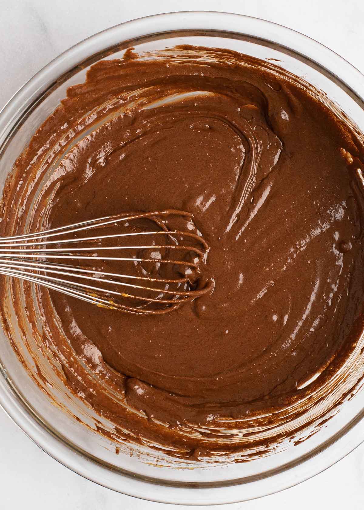 Overhead view of brownie batter in a bowl with a whisk