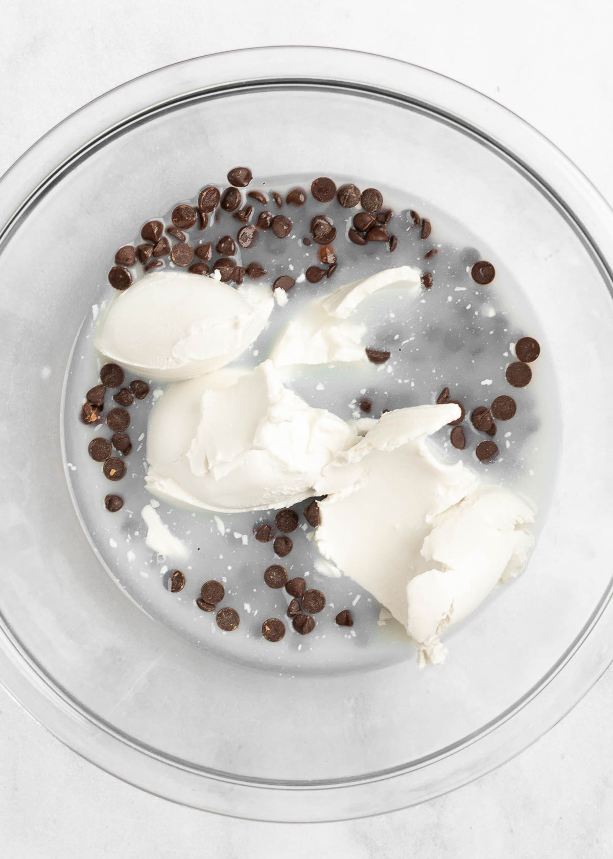 A bowl with solids and liquids from coconut cream, and chocolate chips