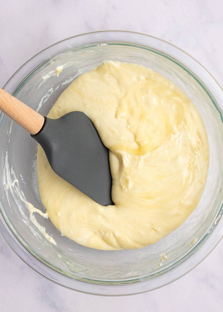 A mixing bowl full of melted cheese, with a rubber spatula in it