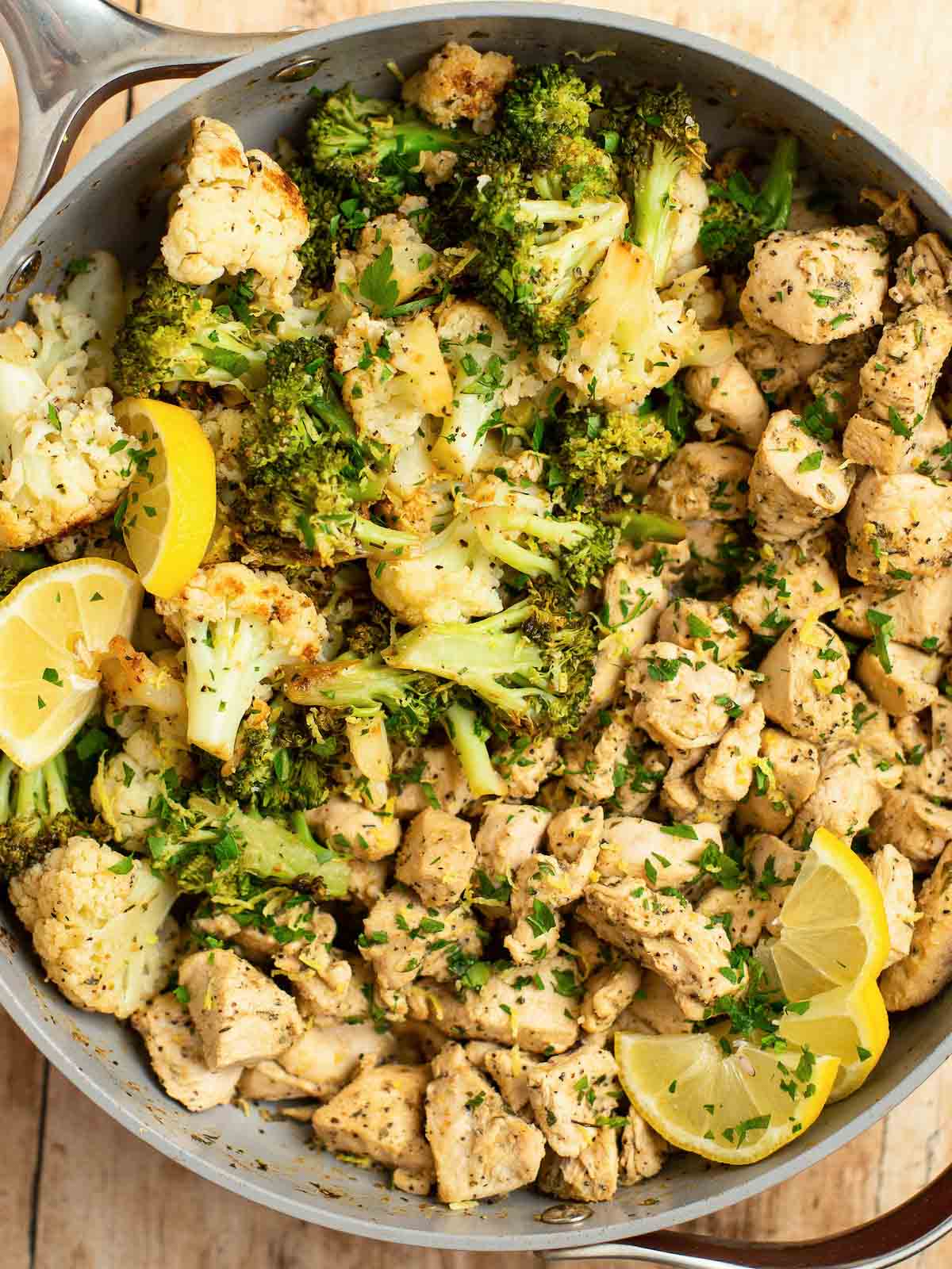 lemon pepper chicken and vegetables in pan with lemon slices