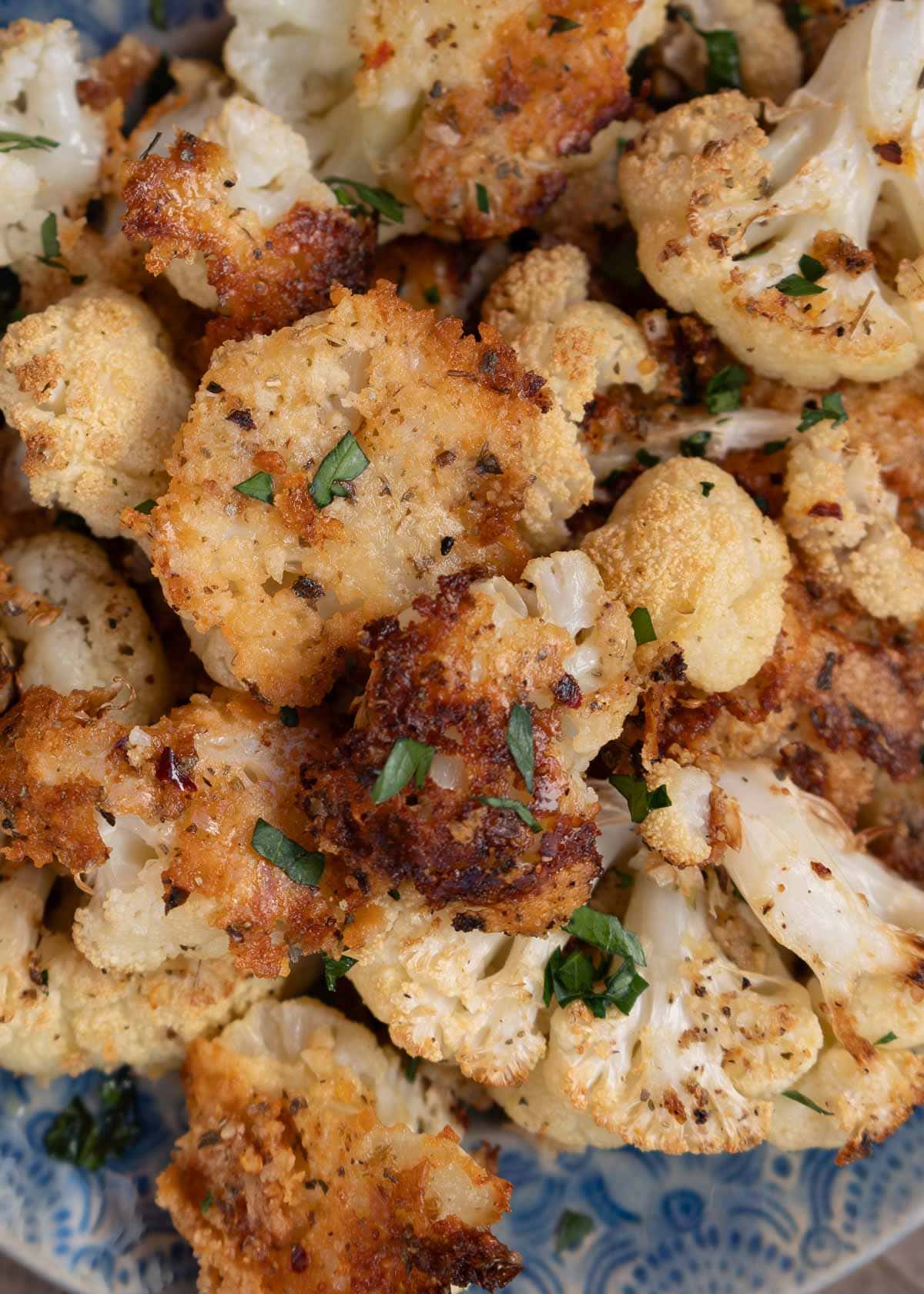 a closeup shot of parmesan cauliflower on a blue plate