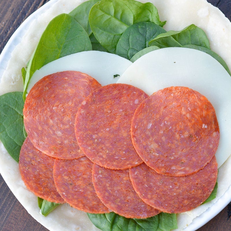 These Pepperoni Cheese Wraps are the perfect keto lunch! Deli pepperoni is paired with smoky provolone, fresh spinach and flavorful pesto aoili, all for about 5 net carbs!