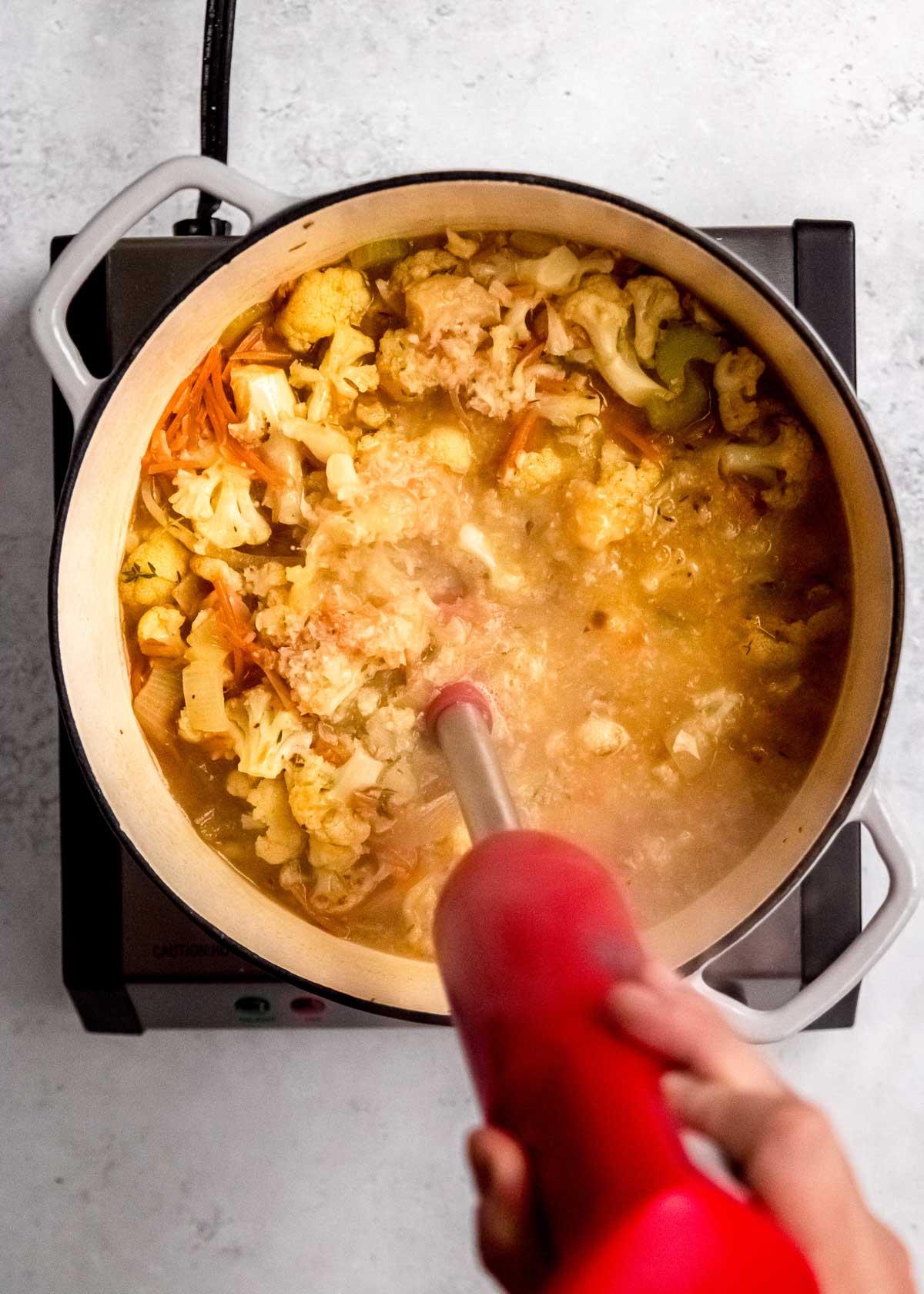 cauliflower soup being blended in dutch oven