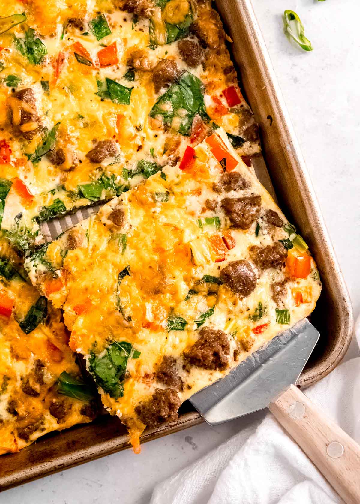 close up of cooked sheet pan eggs on a baking sheet with one slice being removed