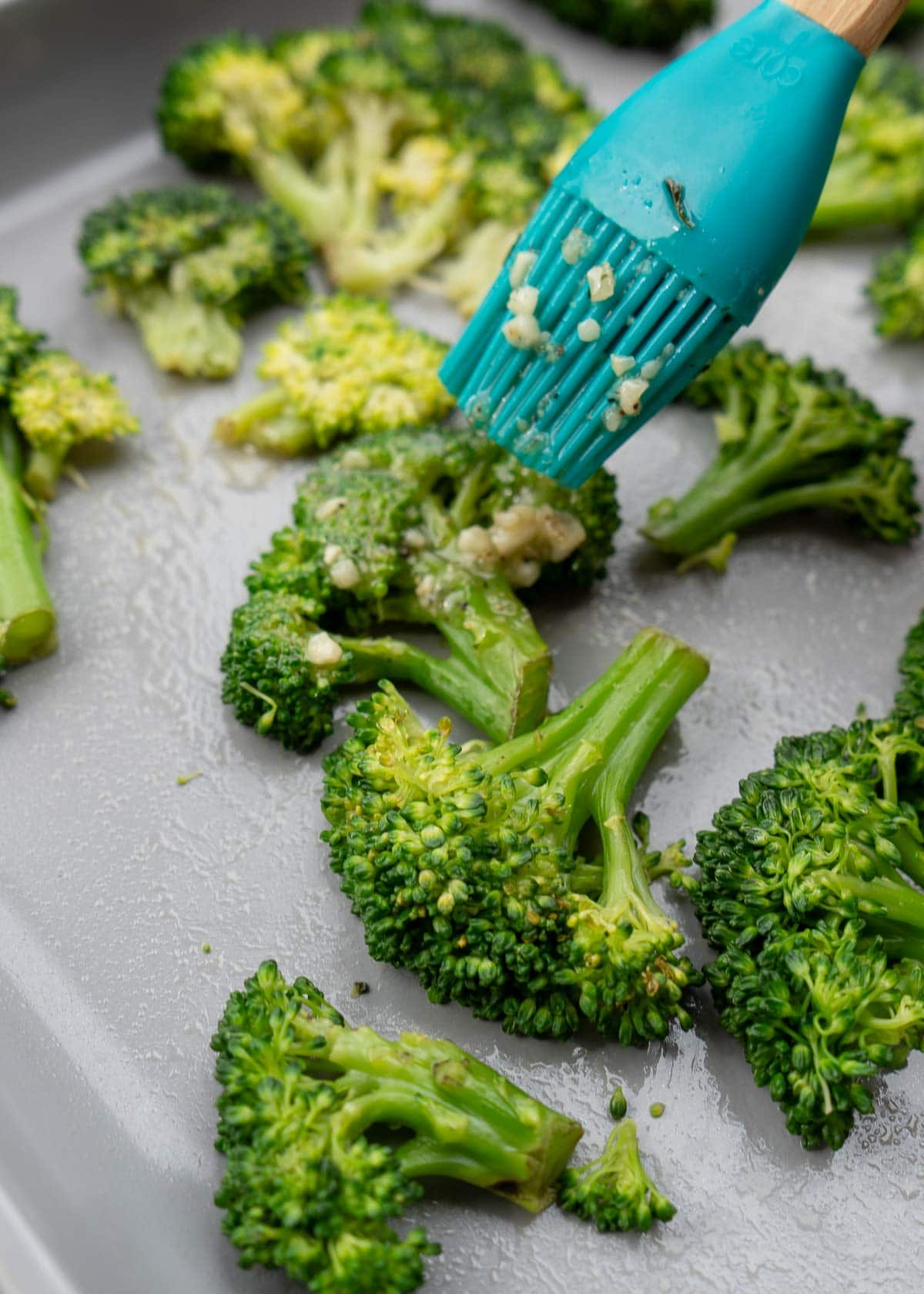 brushing garlic butter mixture on smashed broccoli