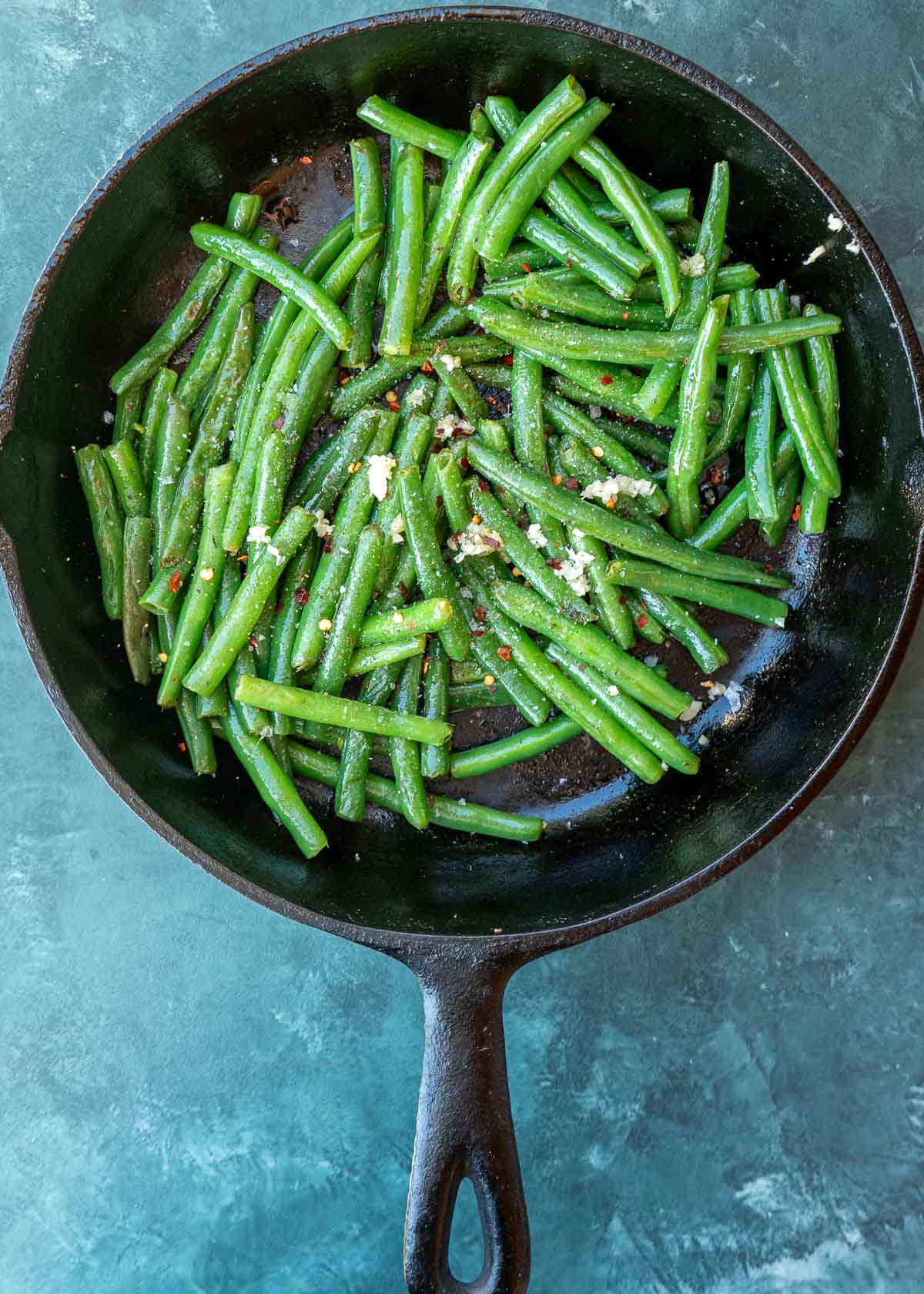 garlic, soy sauce, apple cider vinegar, and brown sugar monk fruit on green beans in a skillet