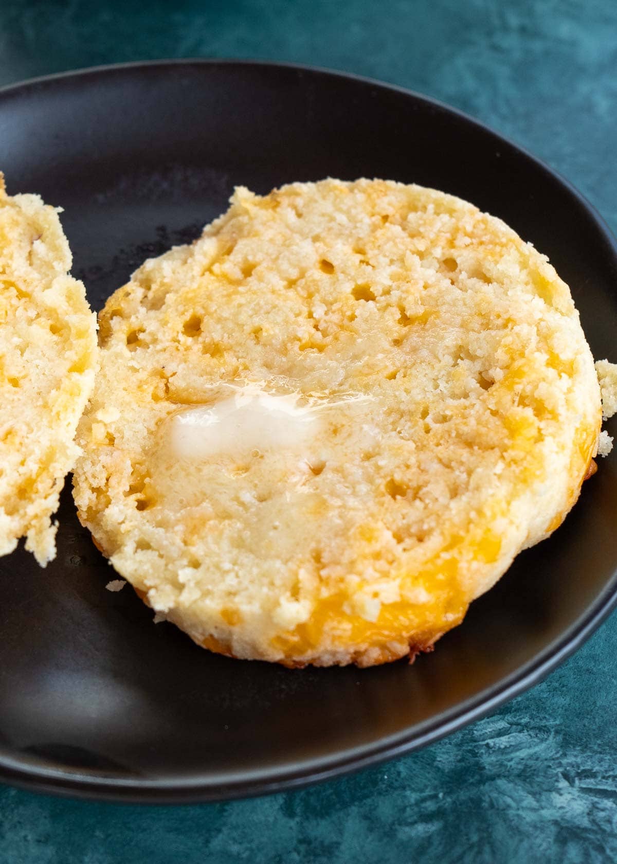 sliced biscuit on a black plate with melted butter