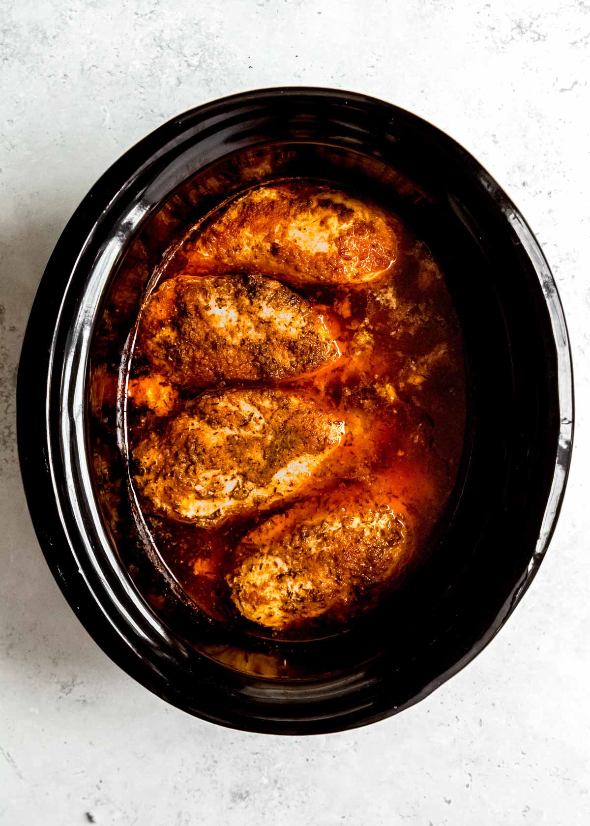 cooked chicken breasts in black slow cooker